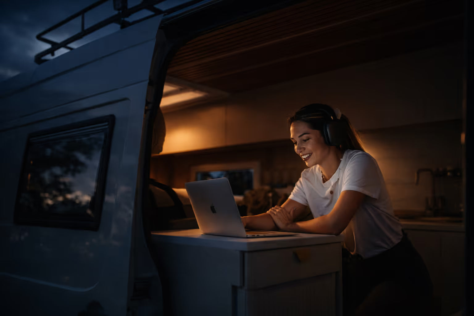 Remote worker using a laptop beside an off-grid campervan